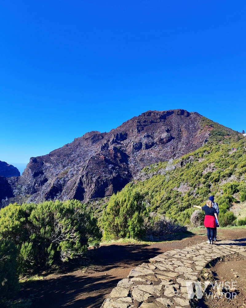 Stone paved mountain path on the PR 1.2 Vereda do Pico Ruivo hiking trail with central mountain range in the background.
